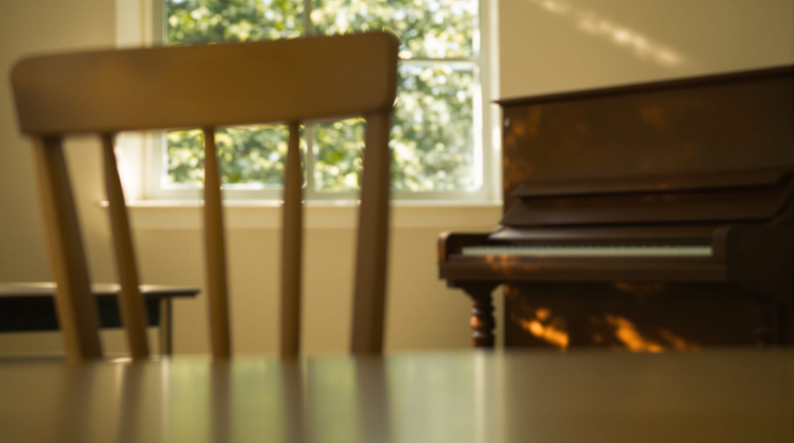 Aula luminosa con un piano vertical y una silla de madera